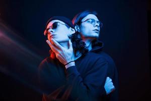 staand samen. portret van tweeling broers. studio schot in donker studio met neon licht foto