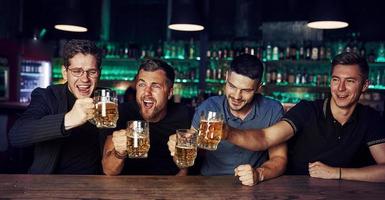 drie sport- fans in een bar aan het kijken voetbal. met bier in handen foto