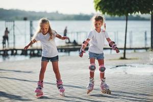 twee schattig kinderen rijden door rol skates in de park Bij dag foto