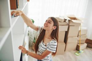 jong huisvrouw reinigt nieuw appartementen. krijgen klaar naar uitpakken de dozen met items foto