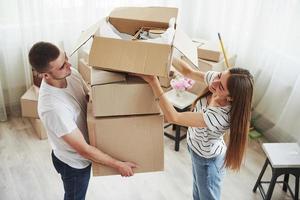 een veel van dozen. vrolijk jong paar in hun nieuw appartement. opvatting van in beweging foto