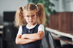 portret van beledigd weinig meisje dat staat binnenshuis met haar armen gekruiste foto