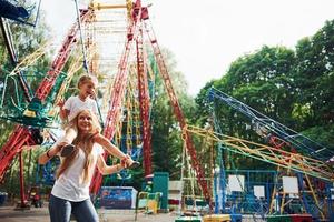 vrolijk weinig meisje haar moeder hebben een mooi zo tijd in de park samen in de buurt attracties foto