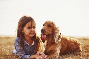 warm en stil. schattig weinig meisje hebben een wandelen met haar hond buitenshuis Bij zonnig dag foto