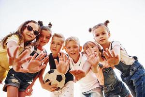 Hallo, gebaar. met voetbal bal. portret van kinderen dat staand samen en poseren voor de camera foto