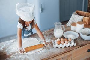 schattig kind in wit chef uniform voorbereidingen treffen voedsel Aan de keuken foto