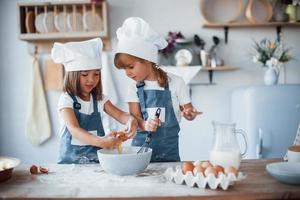 familie kinderen in wit chef uniform voorbereidingen treffen voedsel Aan de keuken foto