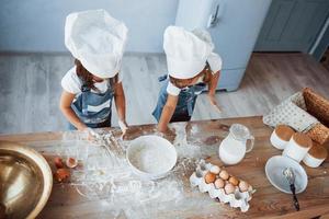 top visie. familie kinderen in wit chef uniform voorbereidingen treffen voedsel Aan de keuken foto