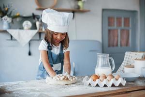 schattig kind in wit chef uniform voorbereidingen treffen voedsel Aan de keuken foto