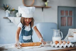 schattig kind in wit chef uniform voorbereidingen treffen voedsel Aan de keuken foto