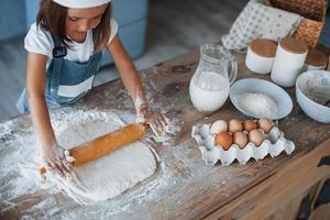 schattig kind in wit chef uniform voorbereidingen treffen voedsel Aan de keuken foto