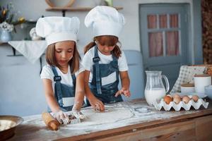 familie kinderen in wit chef uniform voorbereidingen treffen voedsel Aan de keuken foto