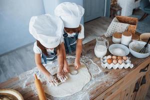 top visie. familie kinderen in wit chef uniform voorbereidingen treffen voedsel Aan de keuken foto