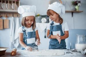 concentreren Bij Koken. familie kinderen in wit chef uniform voorbereidingen treffen voedsel Aan de keuken foto