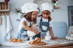 koekjes is klaar. familie kinderen in wit chef uniform voorbereidingen treffen voedsel Aan de keuken foto