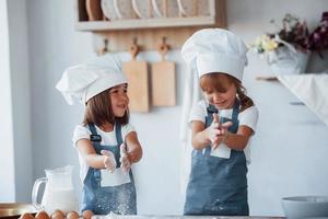 familie kinderen in wit chef uniform voorbereidingen treffen voedsel Aan de keuken foto