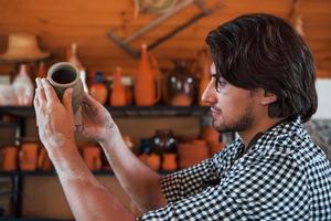 jong keramist houdt vers handgemaakt pot in hand- en looks Bij resultaten van zijn werk foto