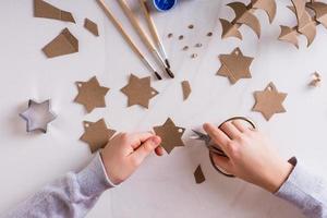 kinderen handen besnoeiing uit sterren van karton voor diy Kerstmis handgemaakt decoraties. top visie. foto