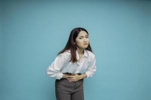 foto van jong onwel ziek ziek vrouw houden hand- Aan maag lijdt pijn geïsoleerd Aan blauw achtergrond