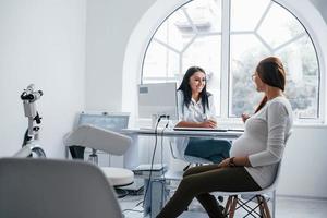 actief gesprek. zwanger vrouw hebben overleg met verloskundige binnenshuis foto