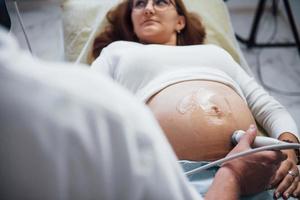mannetje dokter doet echografie voor een zwanger vrouw in de ziekenhuis foto