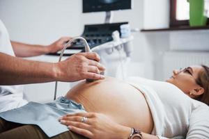 mannetje dokter doet echografie voor een zwanger vrouw in de ziekenhuis foto