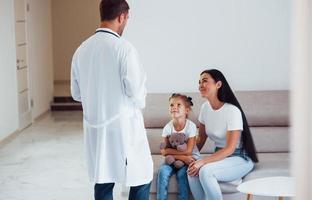 moeder met haar schattig dochter is bezoekende kliniek. luisteren naar de dokter foto