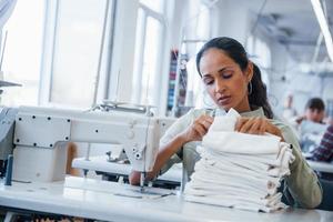 naaister vrouw naait kleren Aan naaien machine in fabriek foto