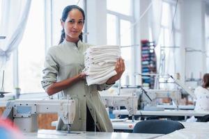 vrouw naaister staat in de fabriek met kleding in handen foto