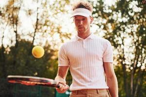jong tennis speler in sportief kleren is Aan de rechtbank buitenshuis foto