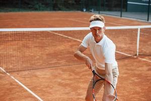 jong tennis speler in sportief kleren is Aan de rechtbank buitenshuis foto