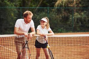 nemen een breken door leunend Aan de netto. twee mensen in sport uniform Toneelstukken tennis samen Aan de rechtbank foto