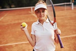 portret van jong vrouw tennis speler in sportief kleren is Aan de rechtbank buitenshuis foto