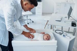 jong kinderarts is met weinig baby in de kliniek Bij dag foto