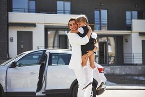 moeder met dochter in school- uniform buitenshuis in de buurt wit auto foto