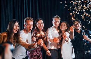 hebben pret met sterretjes. groep van vrolijk vrienden vieren nieuw jaar binnenshuis met drankjes in handen foto