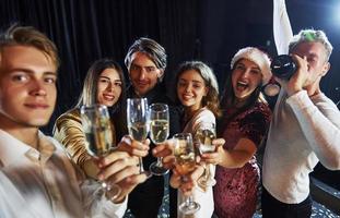 duurt selfie. groep van vrolijk vrienden vieren nieuw jaar binnenshuis met drankjes in handen foto