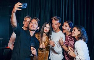 groep van vrolijk vrienden vieren nieuw jaar binnenshuis met drankjes in handen foto