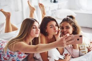 maken selfie door gebruik makend van roze telefoon. gelukkig vrouw vrienden hebben mooi zo tijd Bij pyjama- partij in de slaapkamer foto