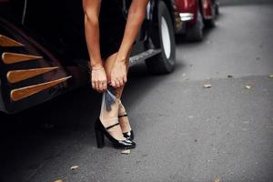 dichtbij omhoog visie van vrouw poten in de buurt oud fashioned auto. met geweer in hand- foto