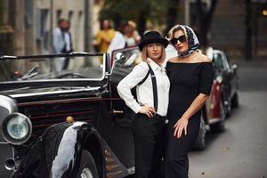 Dames in oud fashioned kleren staat samen in de buurt retro auto foto