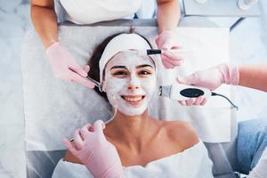 dichtbij omhoog visie van vrouw dat aan het liegen naar beneden in spa salon en hebben gezicht schoonmaak procedure door verschillend apparaten en masker foto