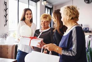 senior vrouw met familie en vrienden vieren een verjaardag binnenshuis foto