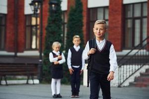 groep van kinderen in school- uniform poseren naar de camera buitenshuis samen in de buurt onderwijs gebouw foto