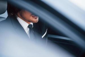 jong zakenman in zwart pak en stropdas binnen modern auto- foto