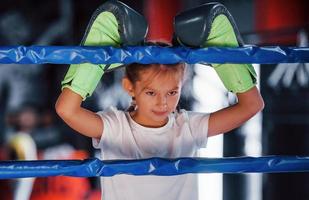 Aan de boksen ring. jong weinig meisje in sportief slijtage is in de Sportschool hebben oefening dag foto