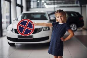 portret van schattig weinig meisje dat houdt weg teken in handen in auto- salon foto