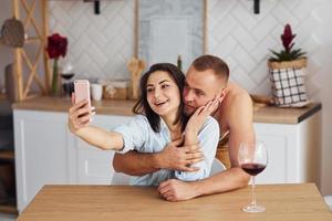 paar samen in de keuken Bij ochtend- tijd met mobiel telefoon foto