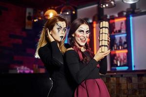 twee vrouw vrienden is Aan de thematisch halloween partij in eng bedenken en kostuums met tijd bom foto