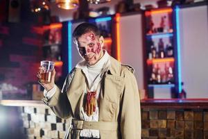 met drinken in hand. portret van Mens dat is Aan de thematisch halloween partij in zombie bedenken en kostuum foto